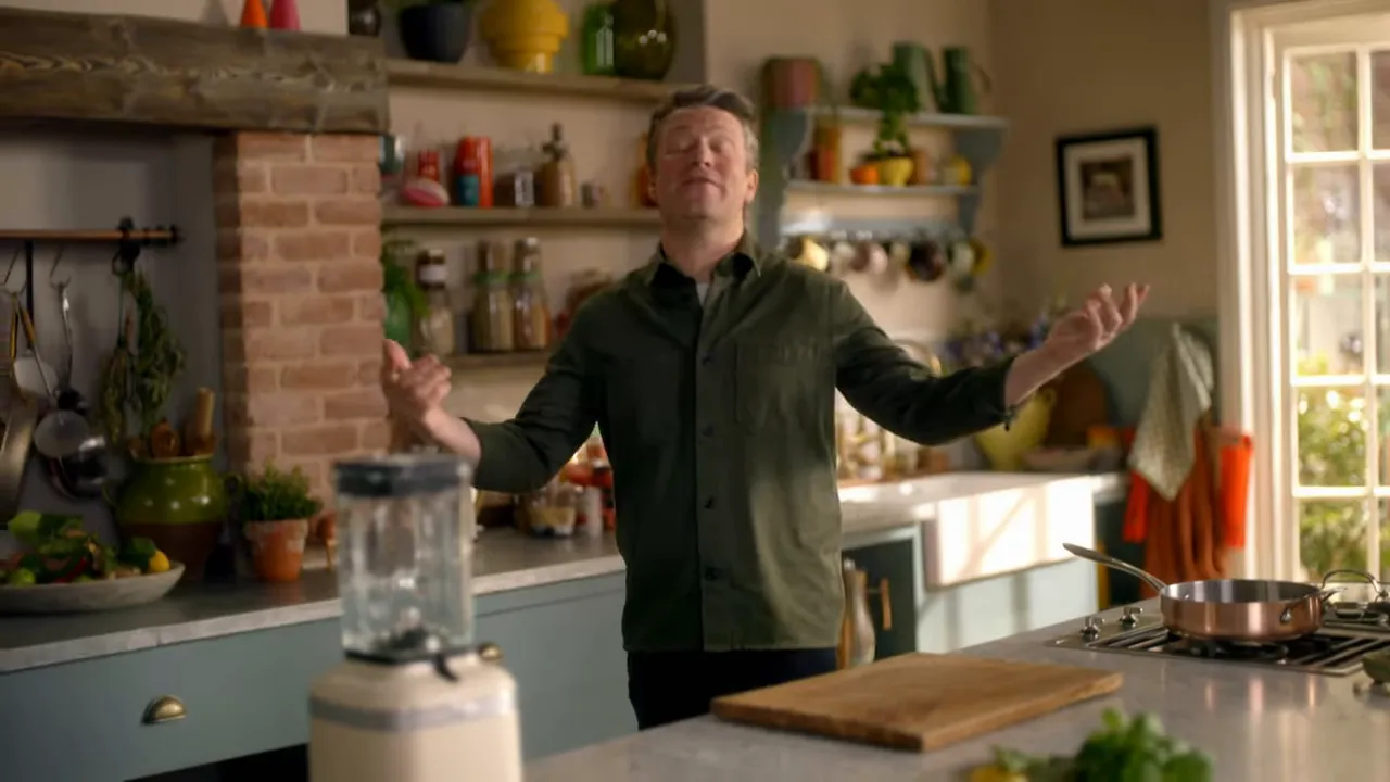 Home kitchen scene with host presenting over counter showing blender, cutting board and stove