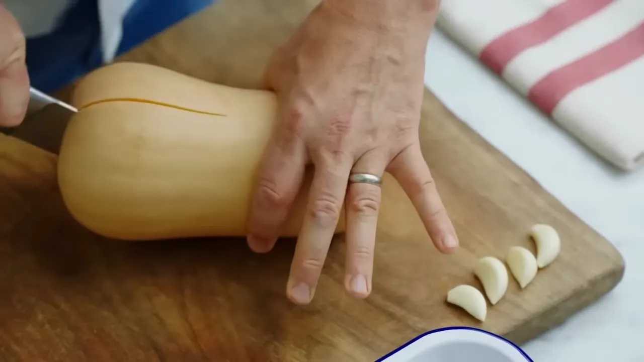 Halved butternut squash in a roasting tray ready to be chopped and seasoned