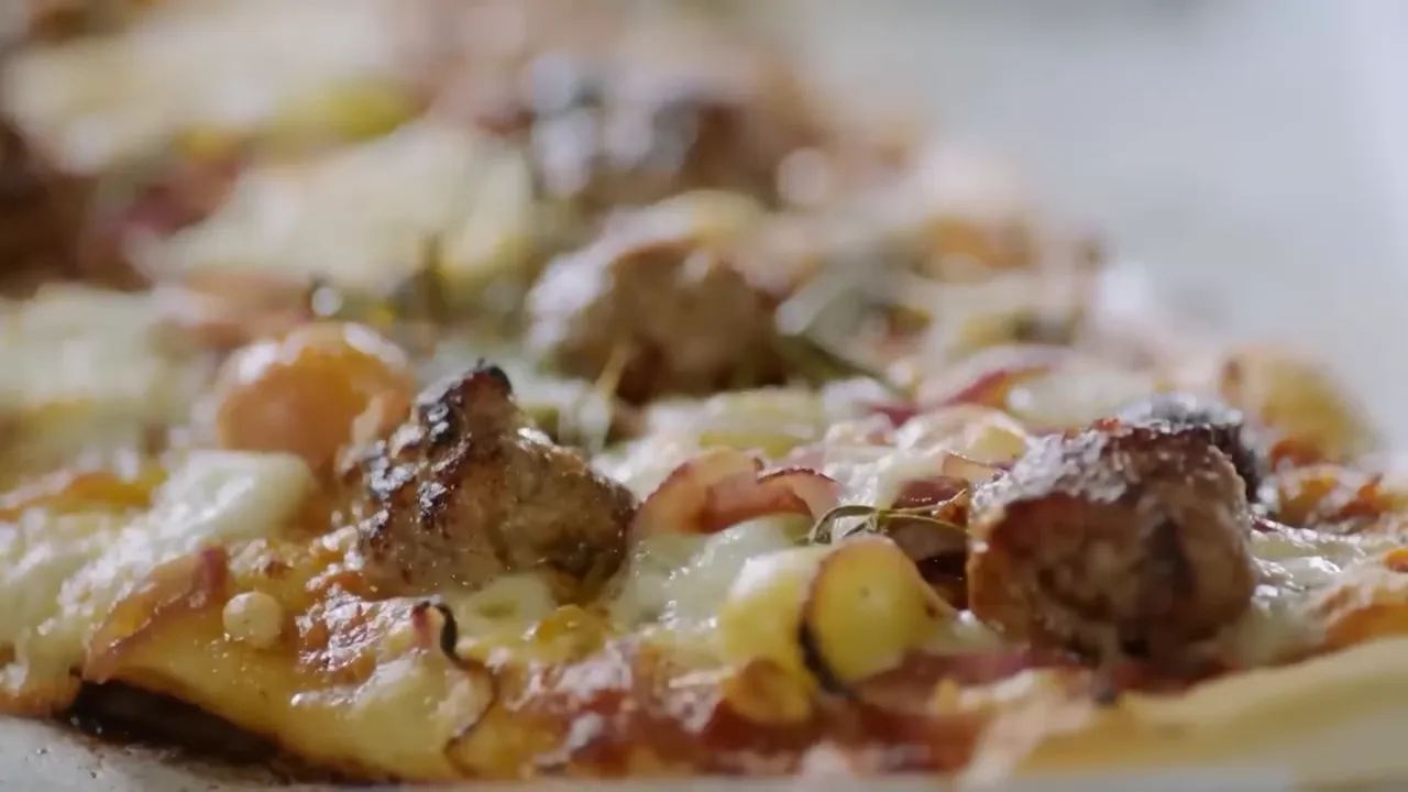 sausage meatballs grapes and pine nuts on pizza slice