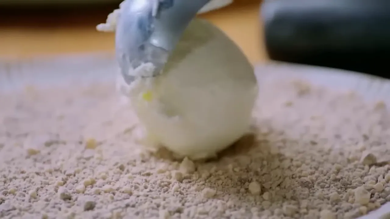 ice cream scoop placing a ball of vanilla ice cream onto a bed of crushed chocolate crumbs