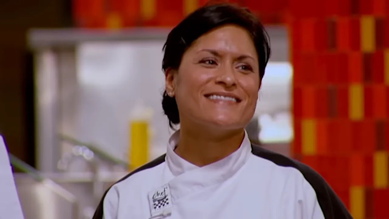 Smiling chef in a white jacket in the Hell’s Kitchen kitchen