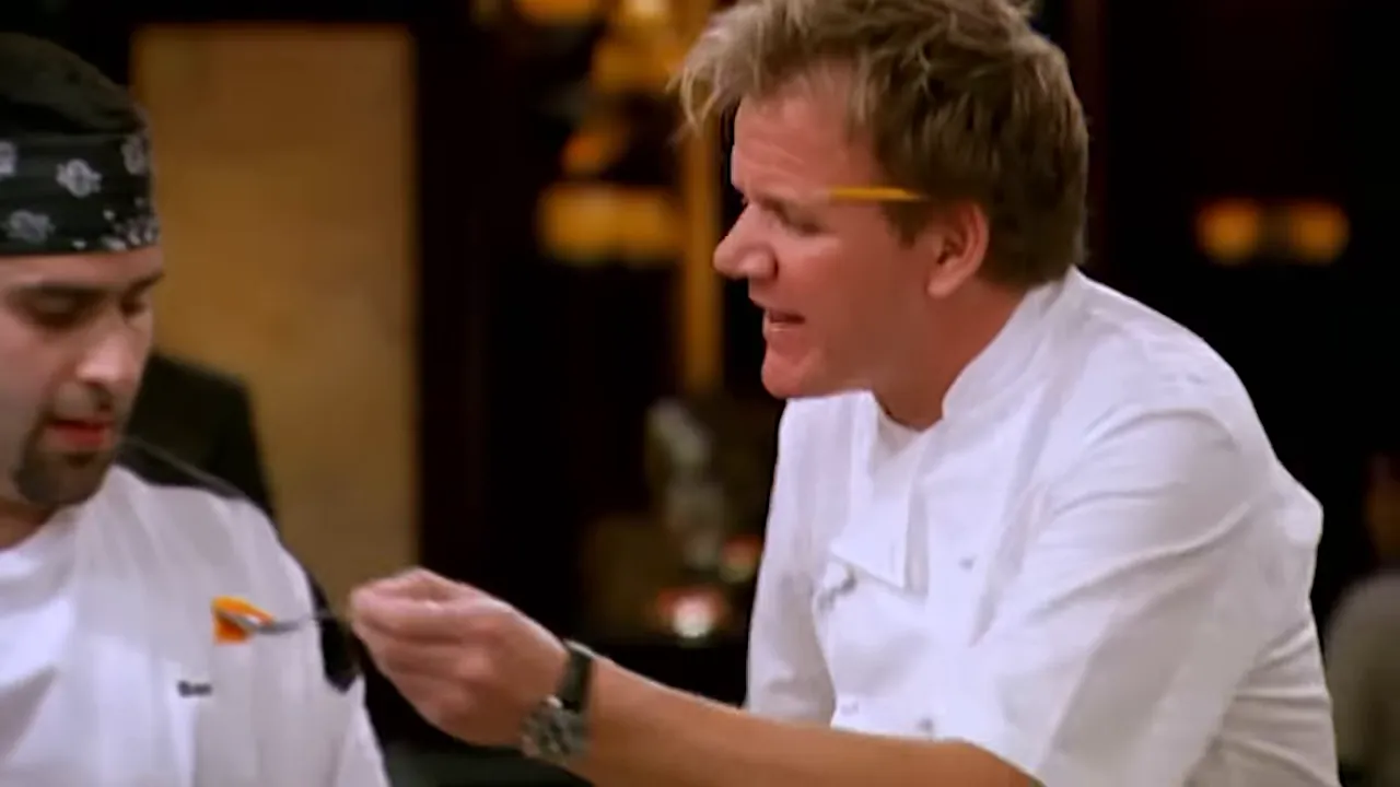 Head chef admonishing a station chef during dinner service while holding a tasting spoon