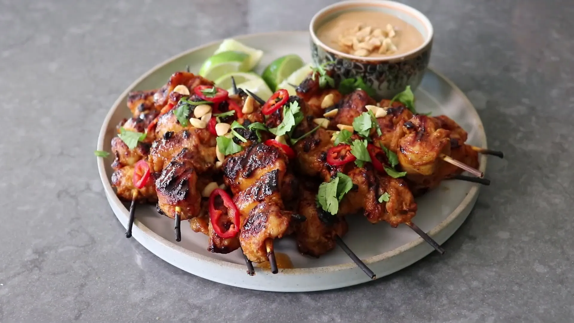 Finished chicken satay served with peanut sauce and garnishes