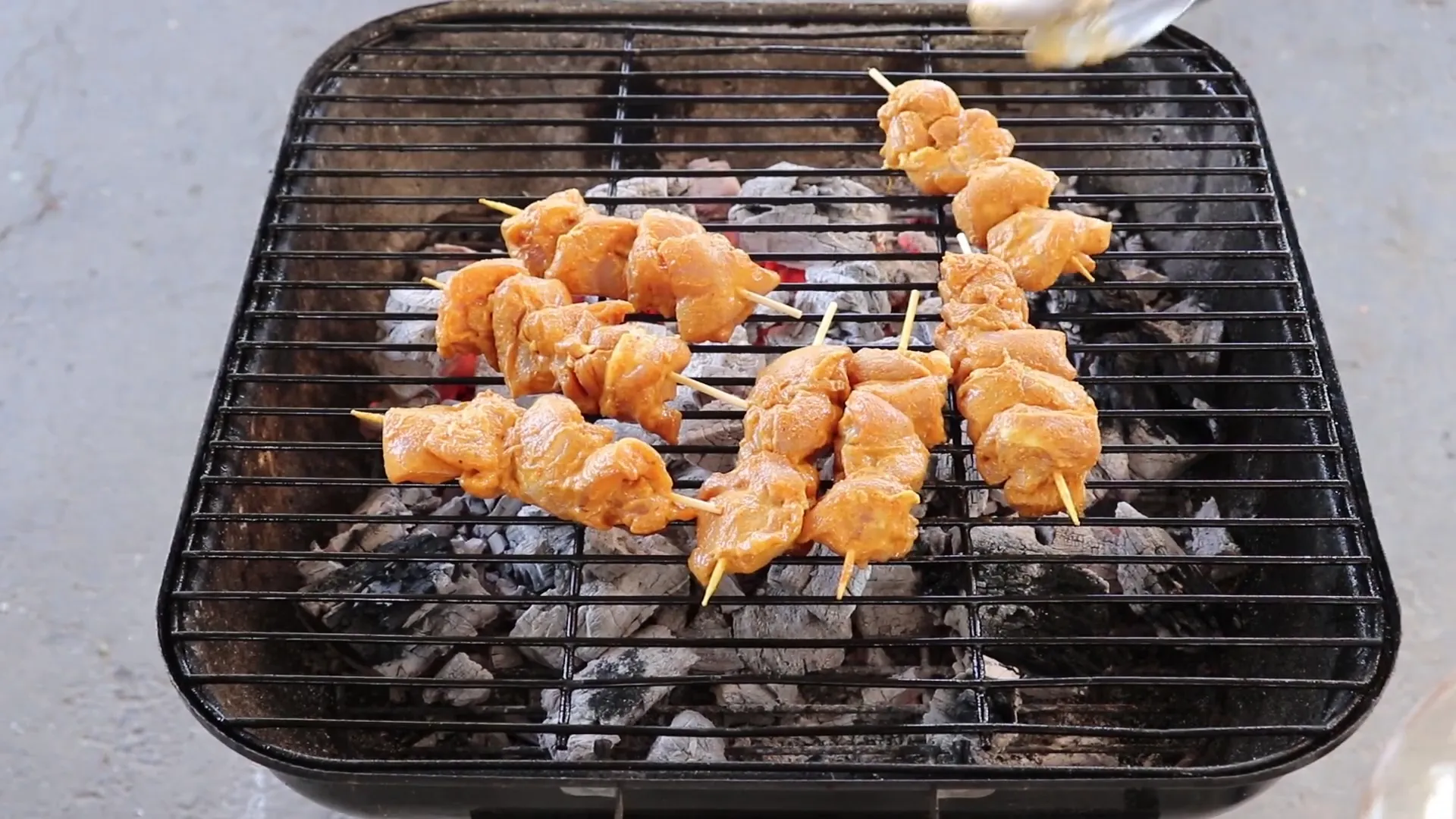 Grilling chicken skewers over hot charcoal