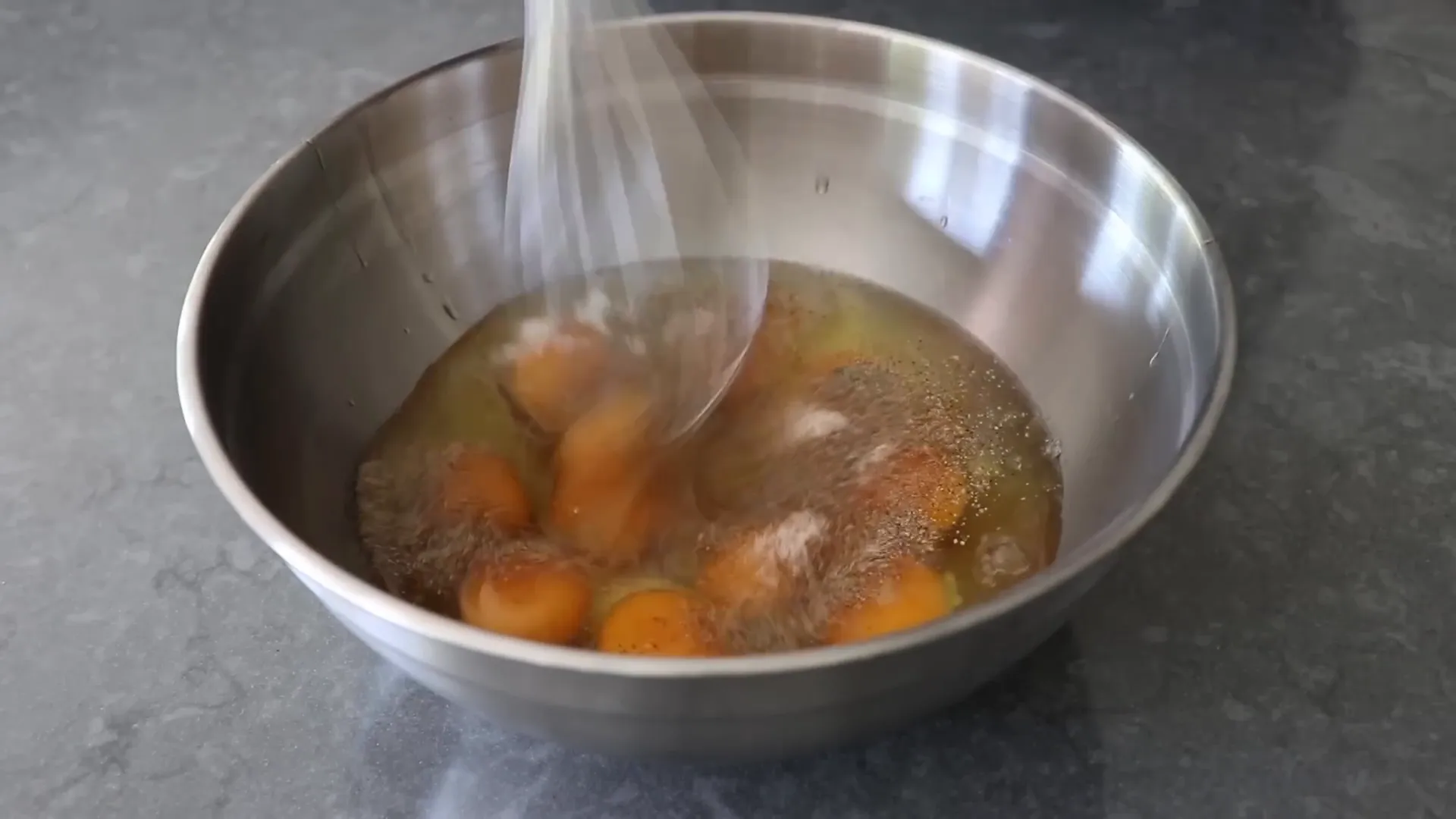 Whisking eggs in a bowl with seasoning