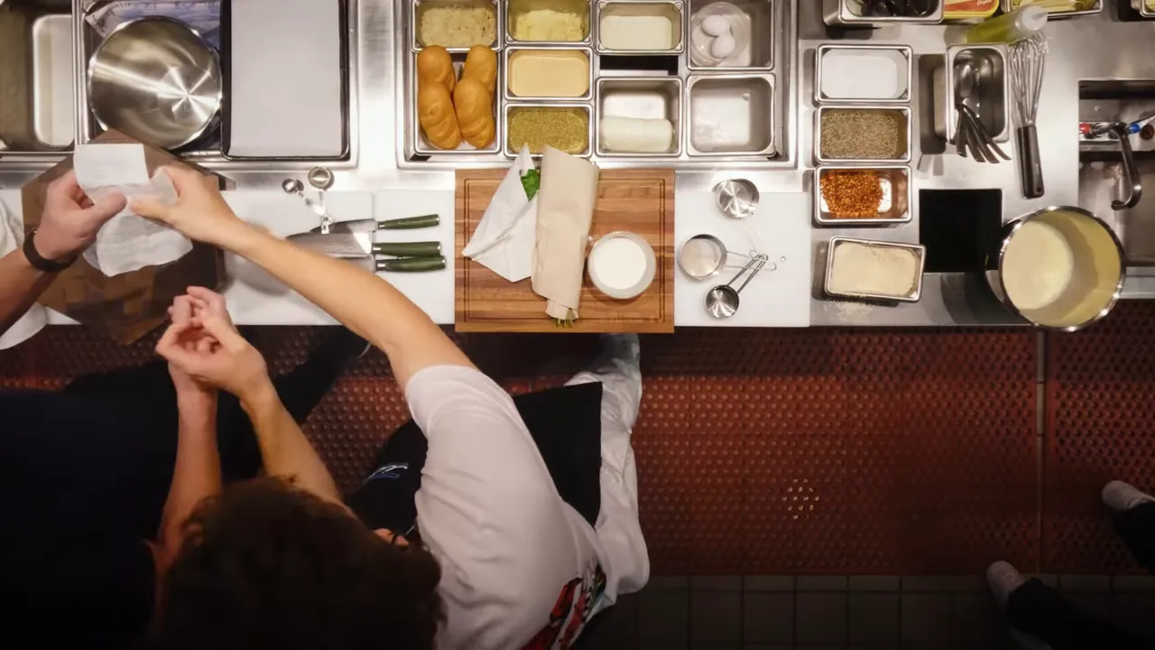 Overhead shot of a prep station with rolls, spices, measuring spoons, and a cutting board
