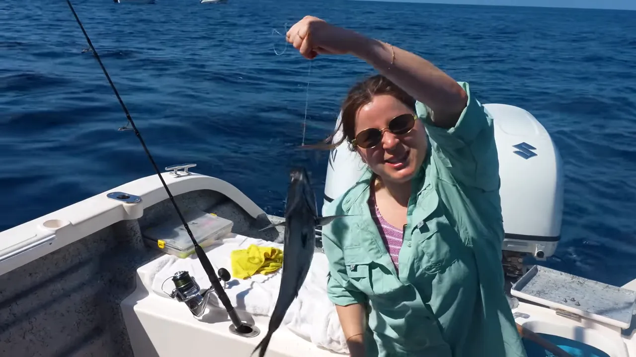 The passenger holding the freshly caught fish on the boat