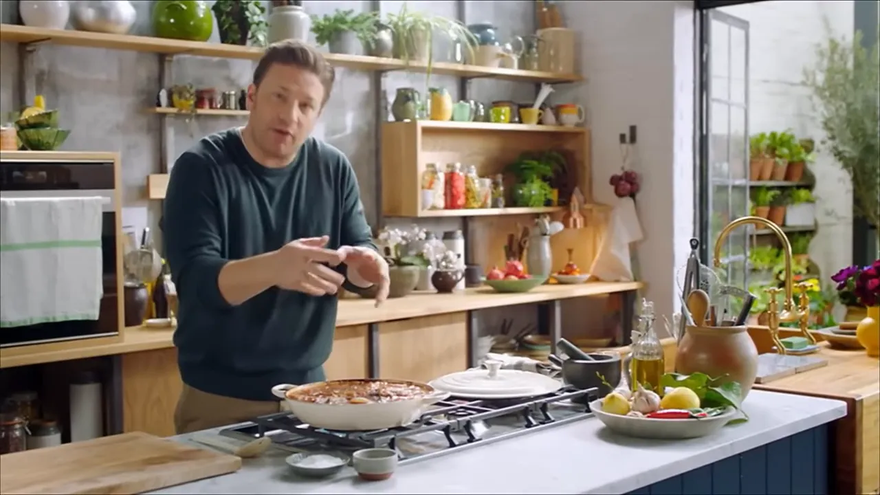assembled aubergine lasagne in a skillet on the kitchen counter with the cook presenting it