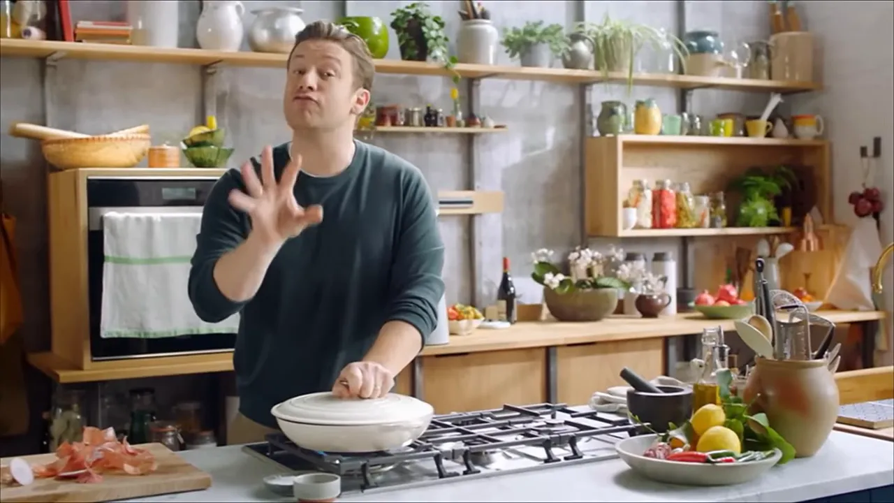 Cook covering a wide pan on a stovetop in a home kitchen