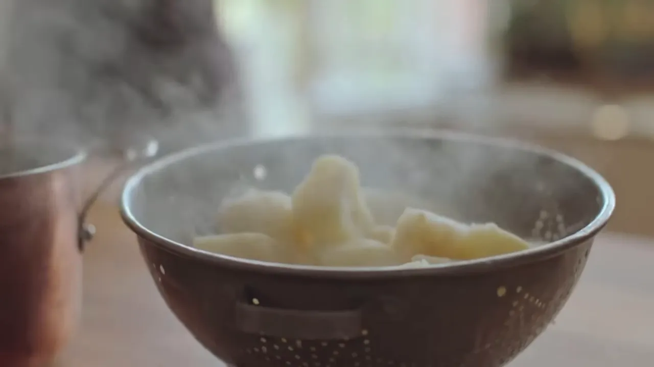 Steaming chunks of potato and celeriac in a metal colander