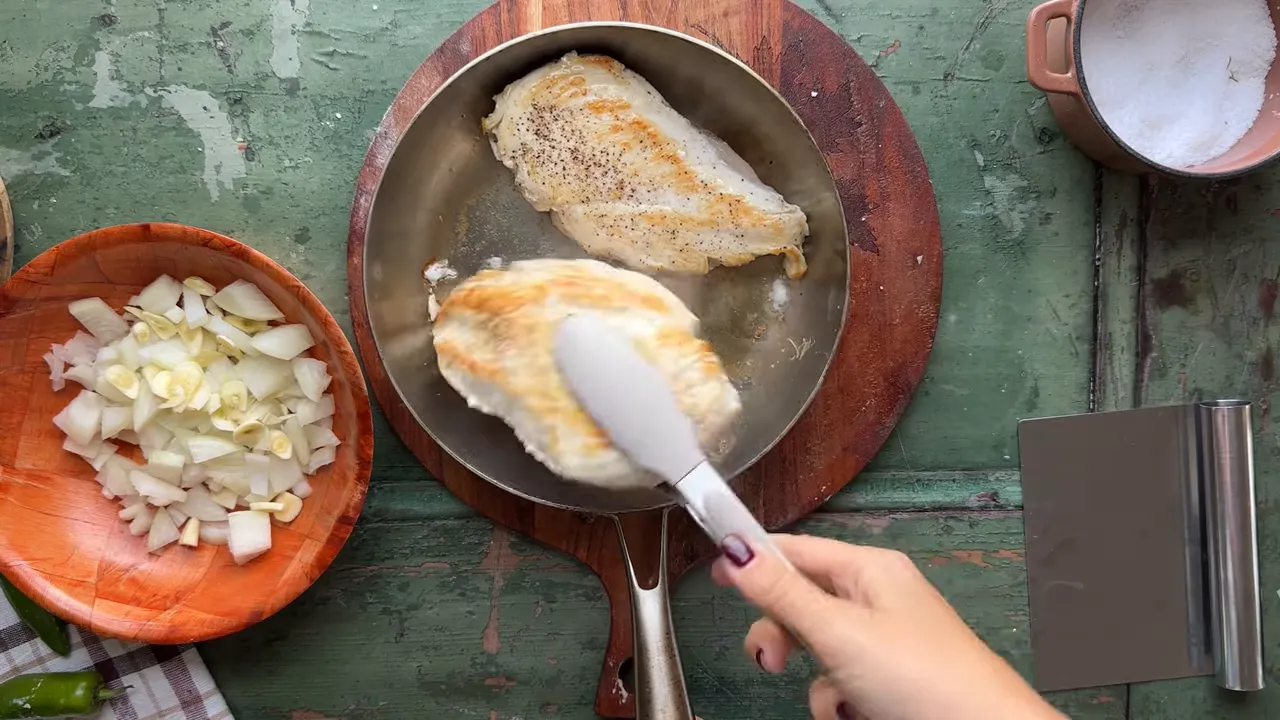Searing seasoned boneless skinless chicken breast in a skillet