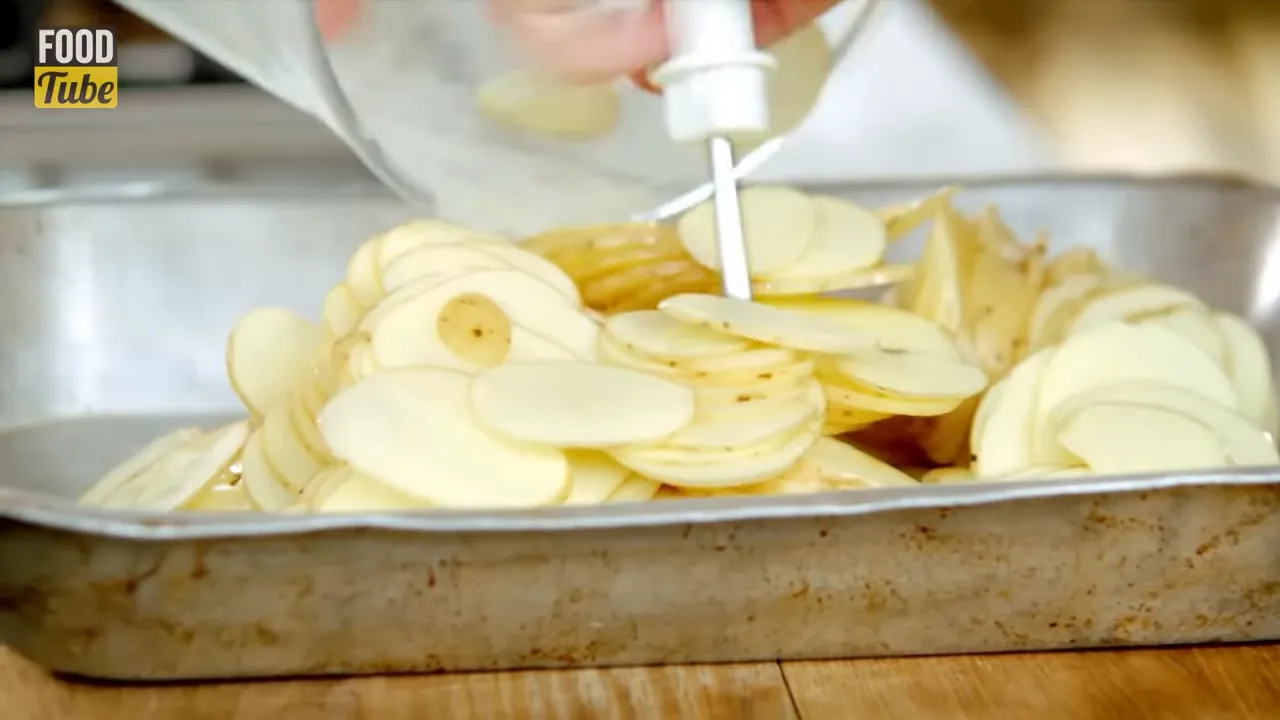 Thinly sliced potatoes layered in a roasting tray ready for dauphinoise