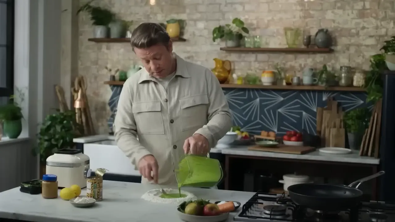 Green spinach batter being poured from a blender jug into a well of flour on a kitchen counter to make flatbreads