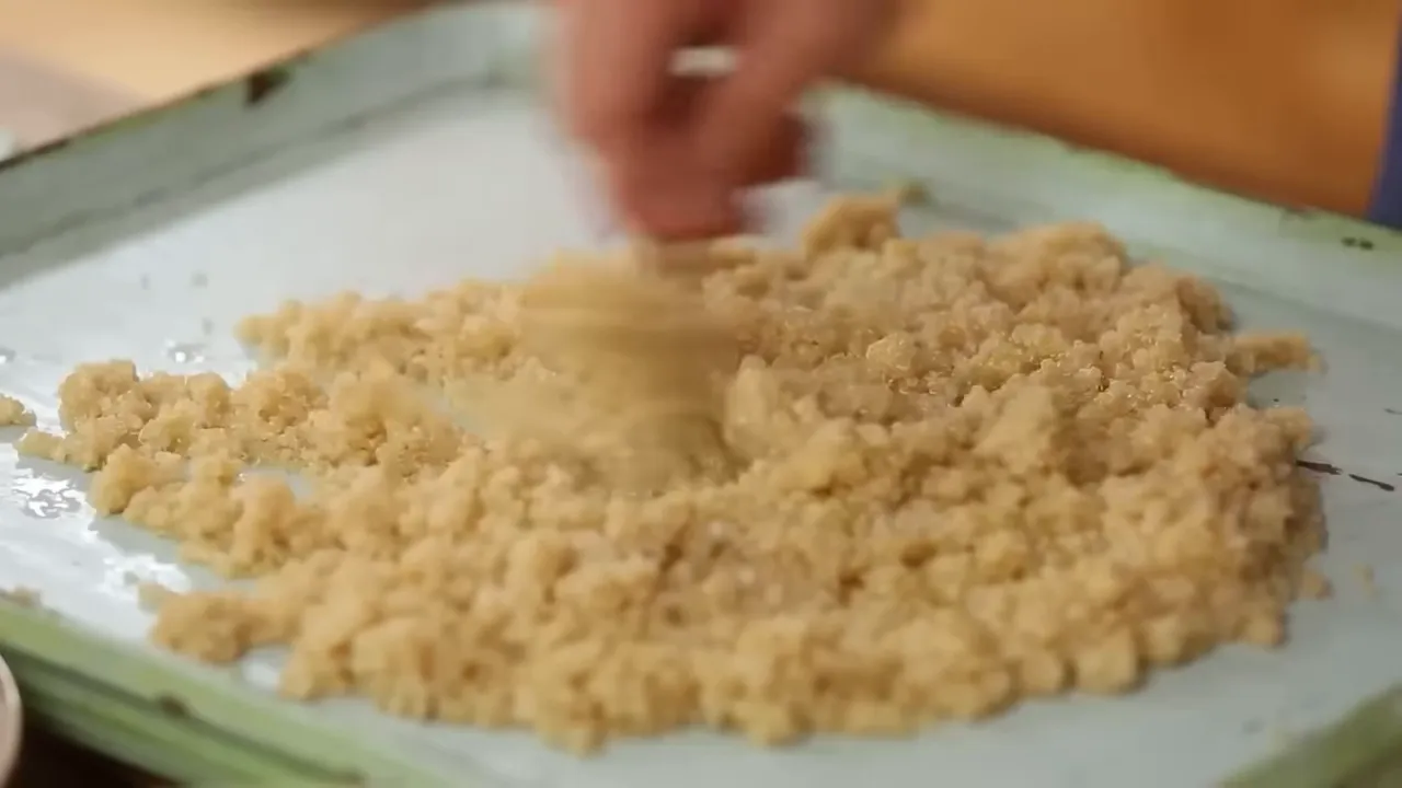 Close-up of fluffy cooked quinoa being stirred on a tray, showing separated grains and texture