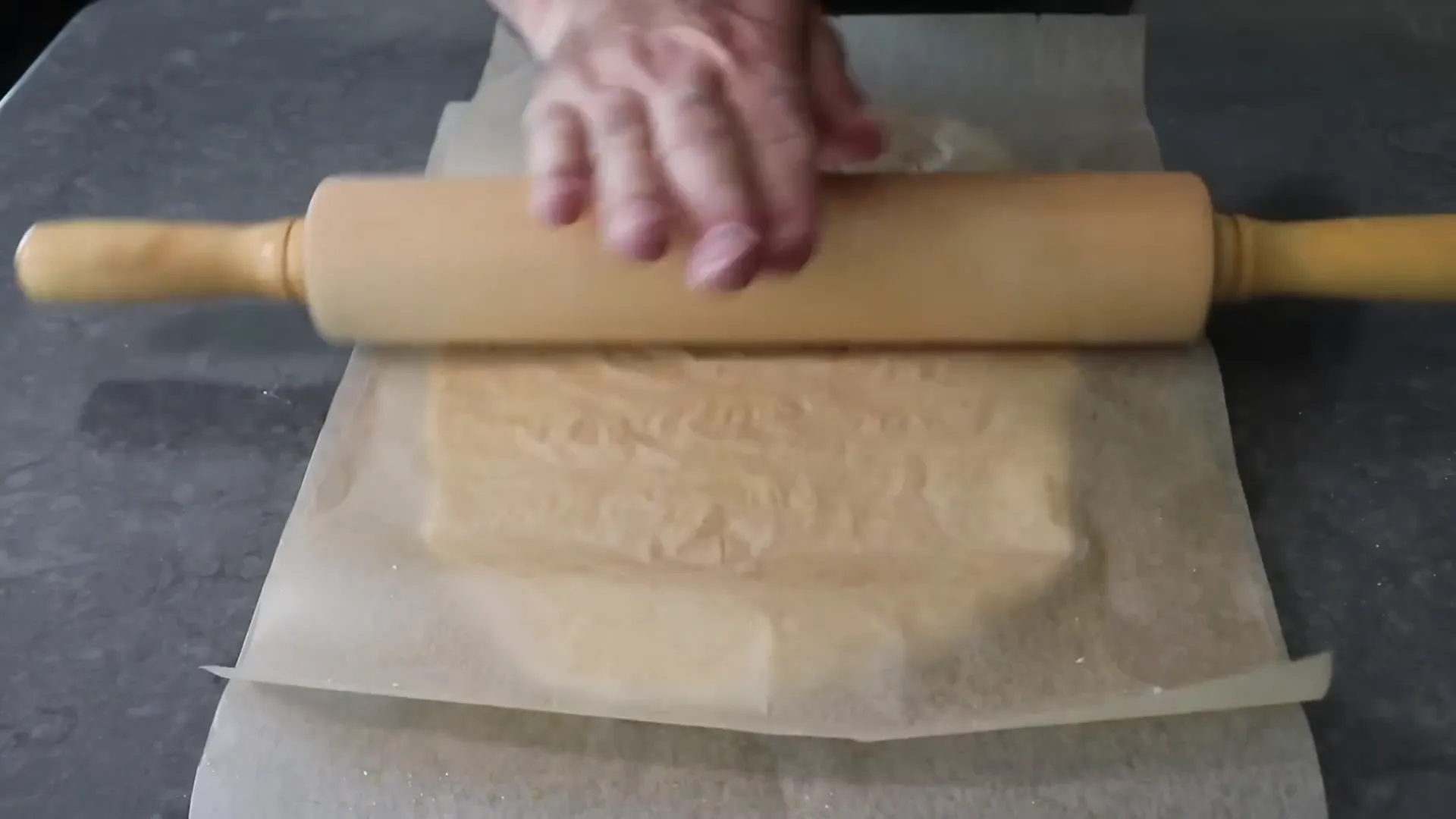 Rolling pizza dough between two oiled parchment sheets