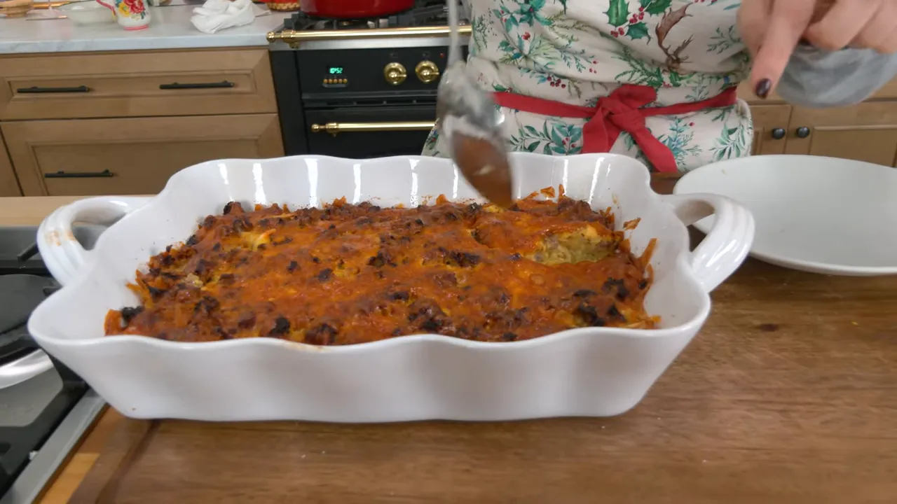 Finished breakfast casserole with melted cheddar and browned sausage in a white baking dish on a wooden counter