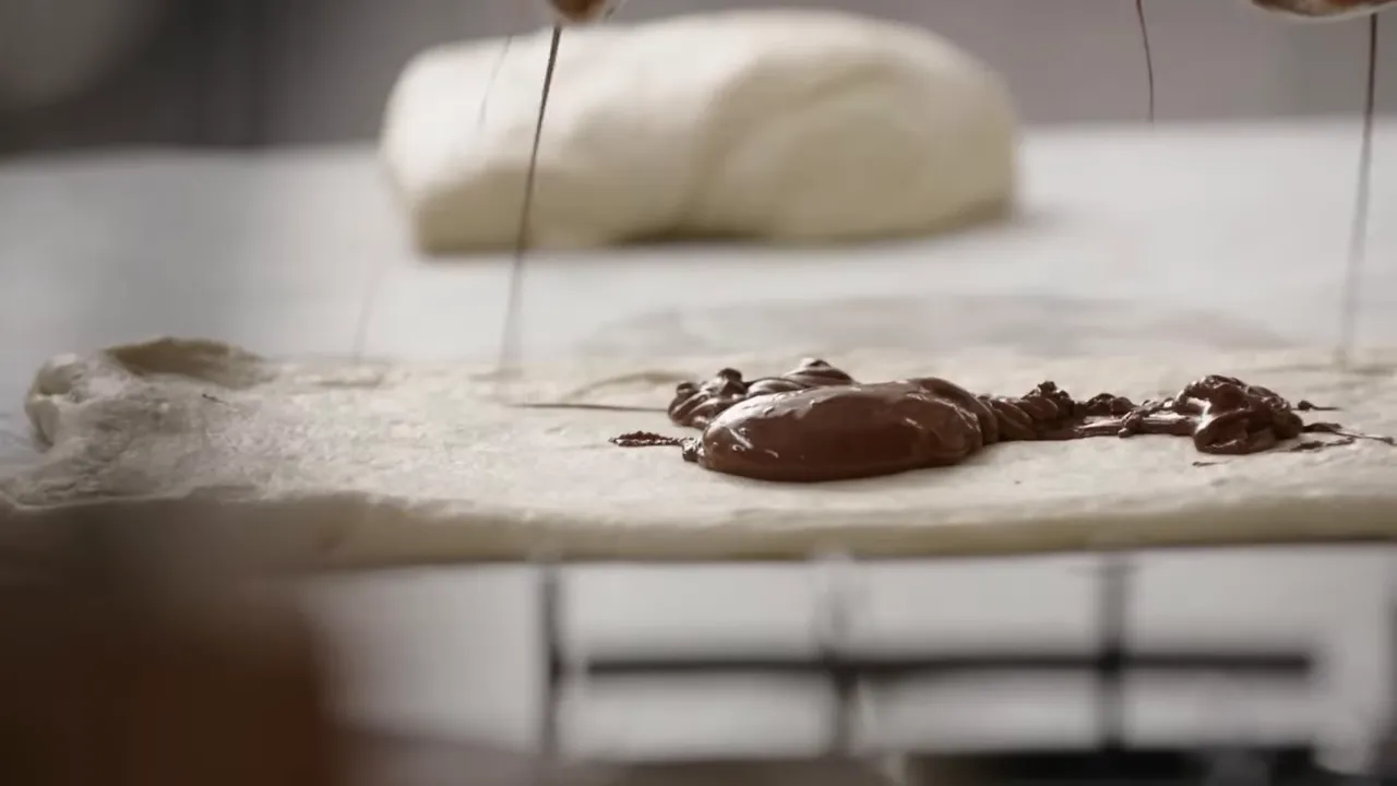 Spreading hazelnut chocolate spread across rolled-out dough