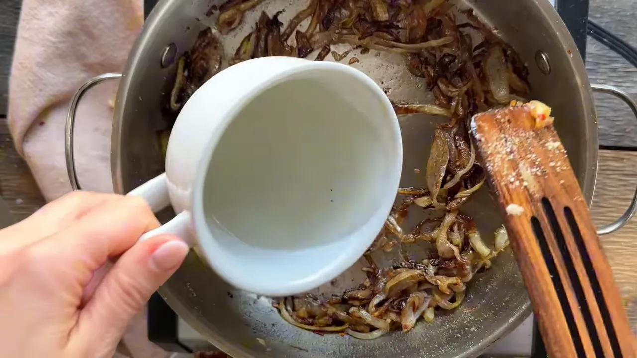 Pouring pasta water into a pan of caramelized onions
