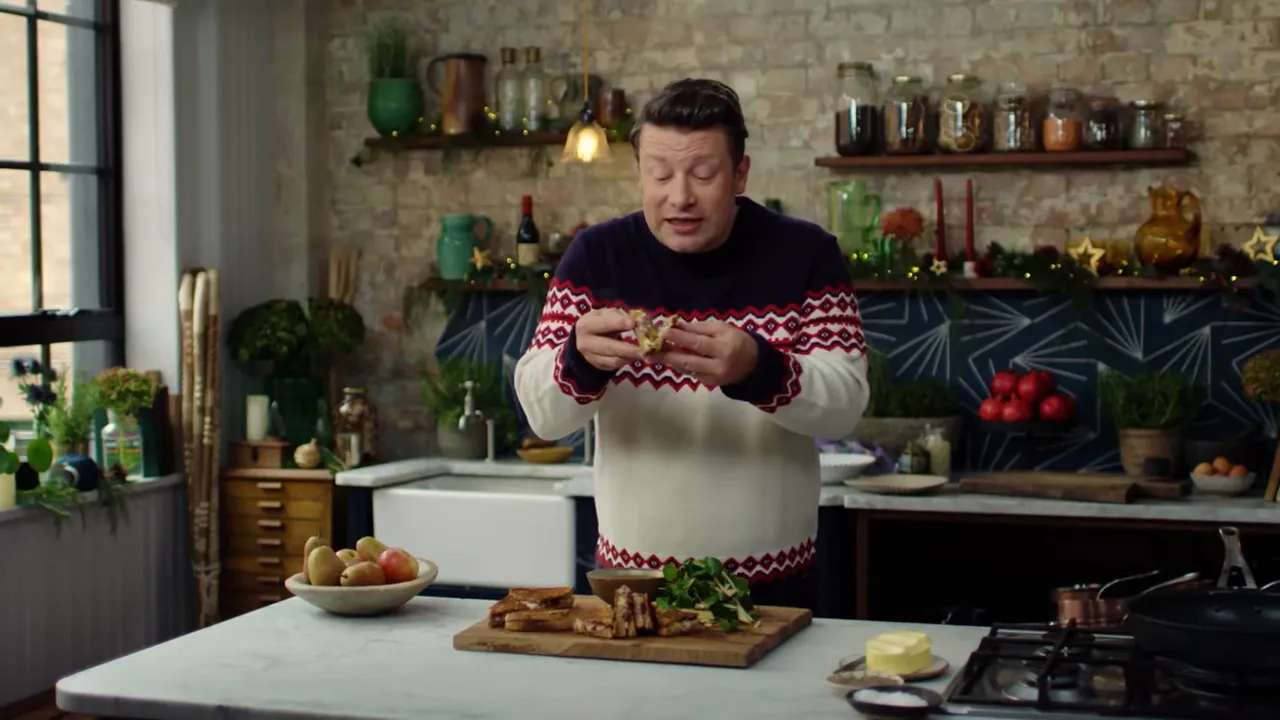 Chef holding and pulling apart a Christmas toastie above a wooden board with salad