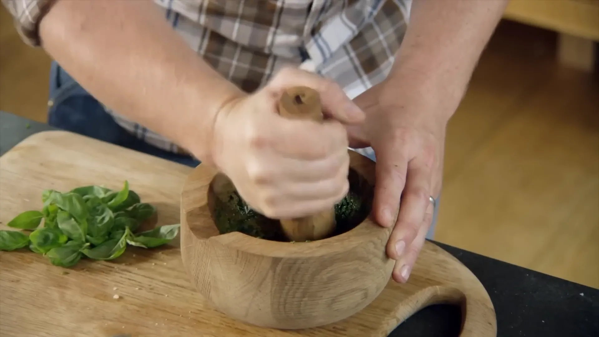 Pounding fresh basil with salt in a pestle and mortar