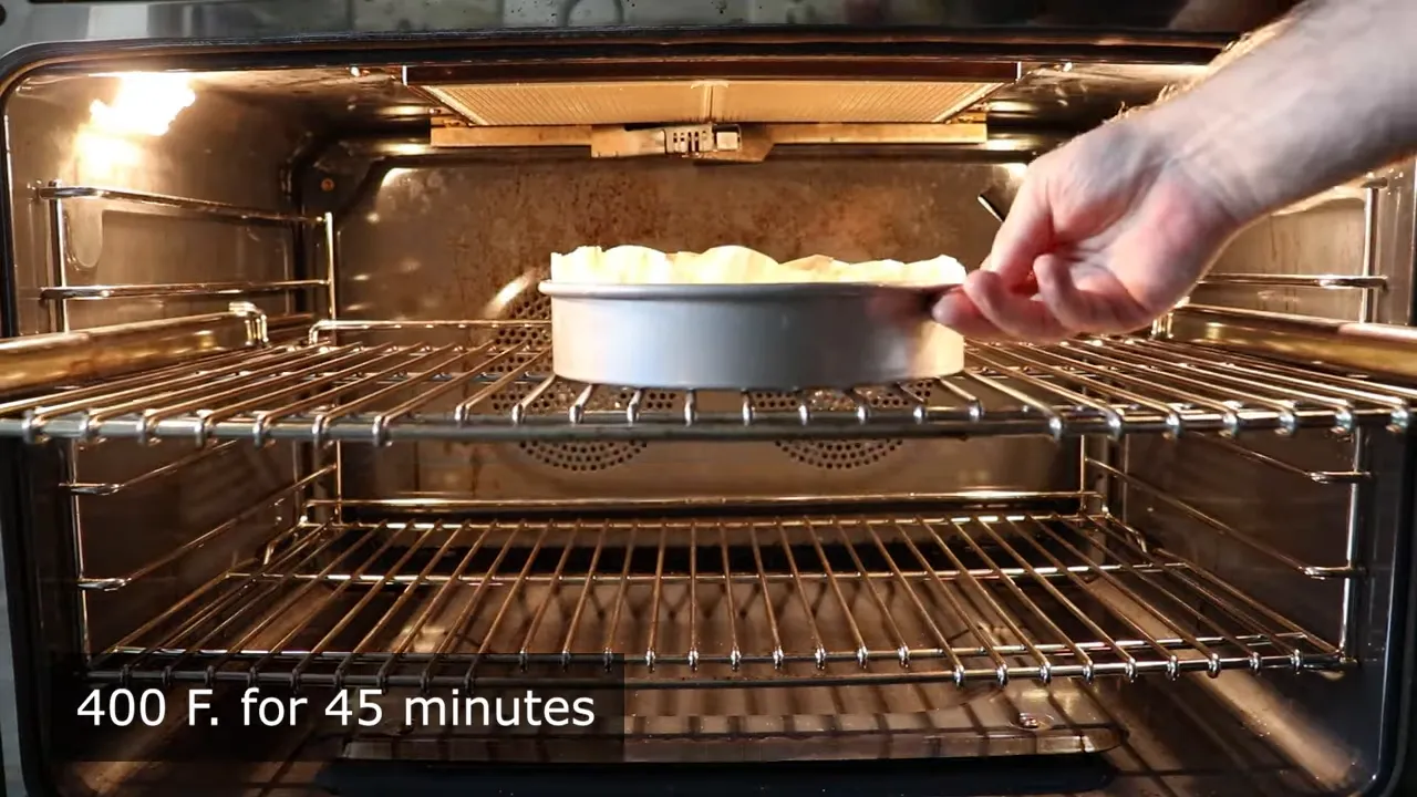 Hand placing cheesecake pan into the oven on the upper rack
