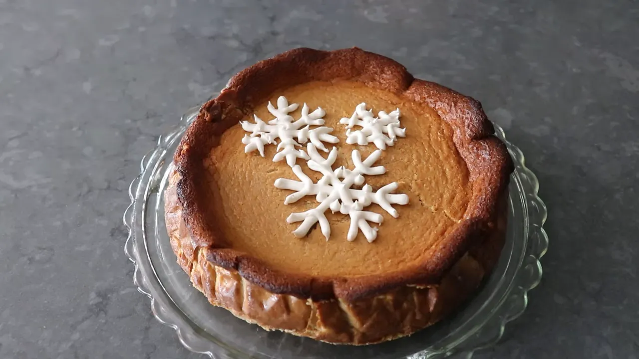Gingerbread Basque cheesecake topped with three royal icing snowflake decorations on a glass stand