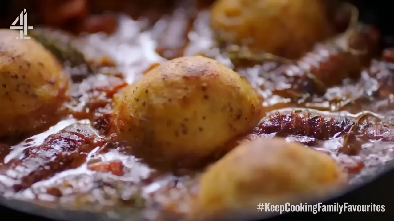 Close-up of golden potato dumplings sitting in a rich, glossy sausage casserole sauce