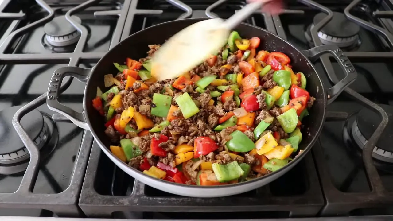Stirring rice and peppers into the meat