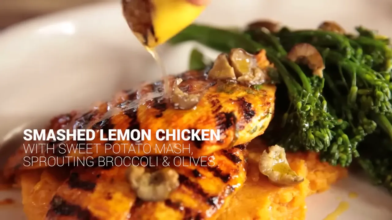 chargrilled lemon chicken on sweet potato mash with sprouting broccoli and lemon juice being squeezed over it