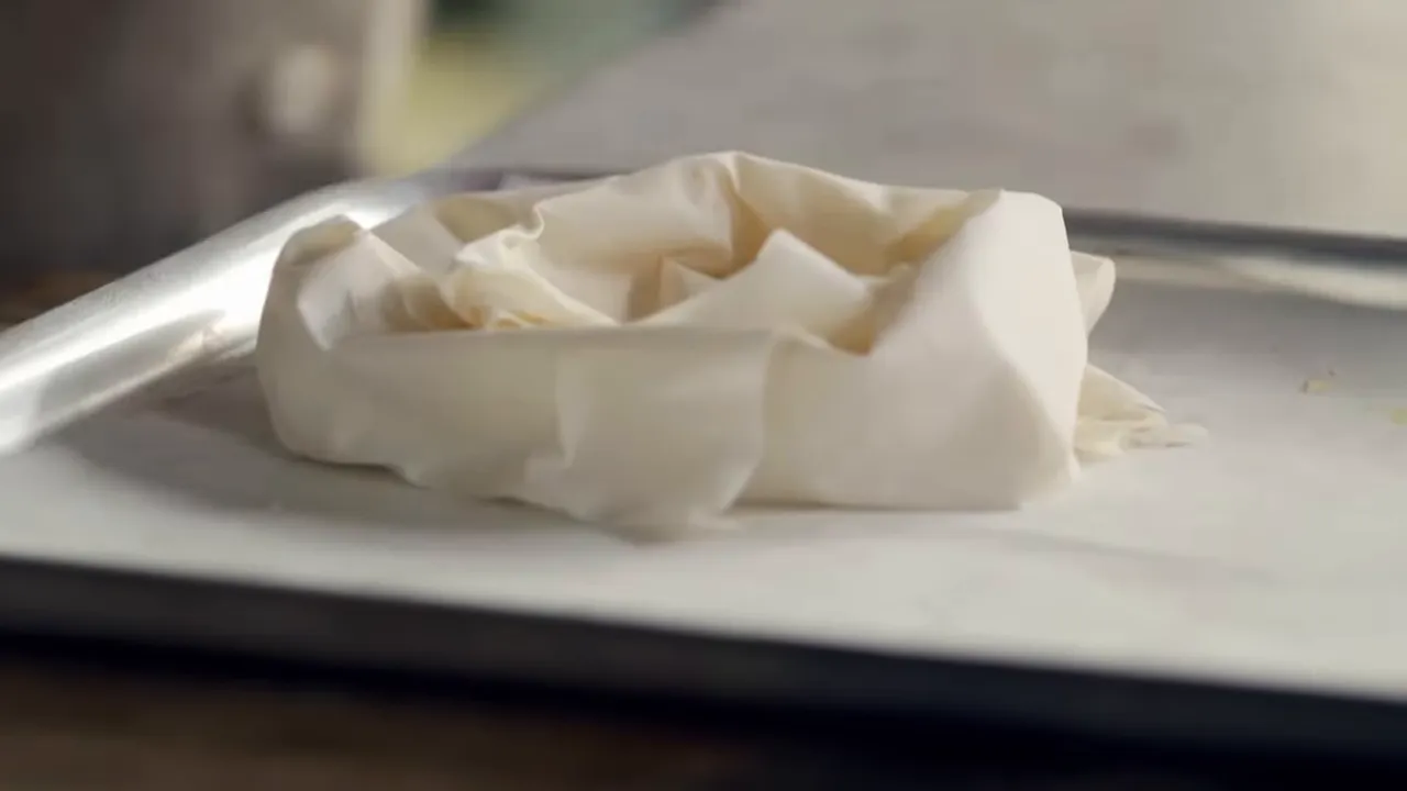 Filo pastry shaped into a nest on a parchment-lined baking tray
