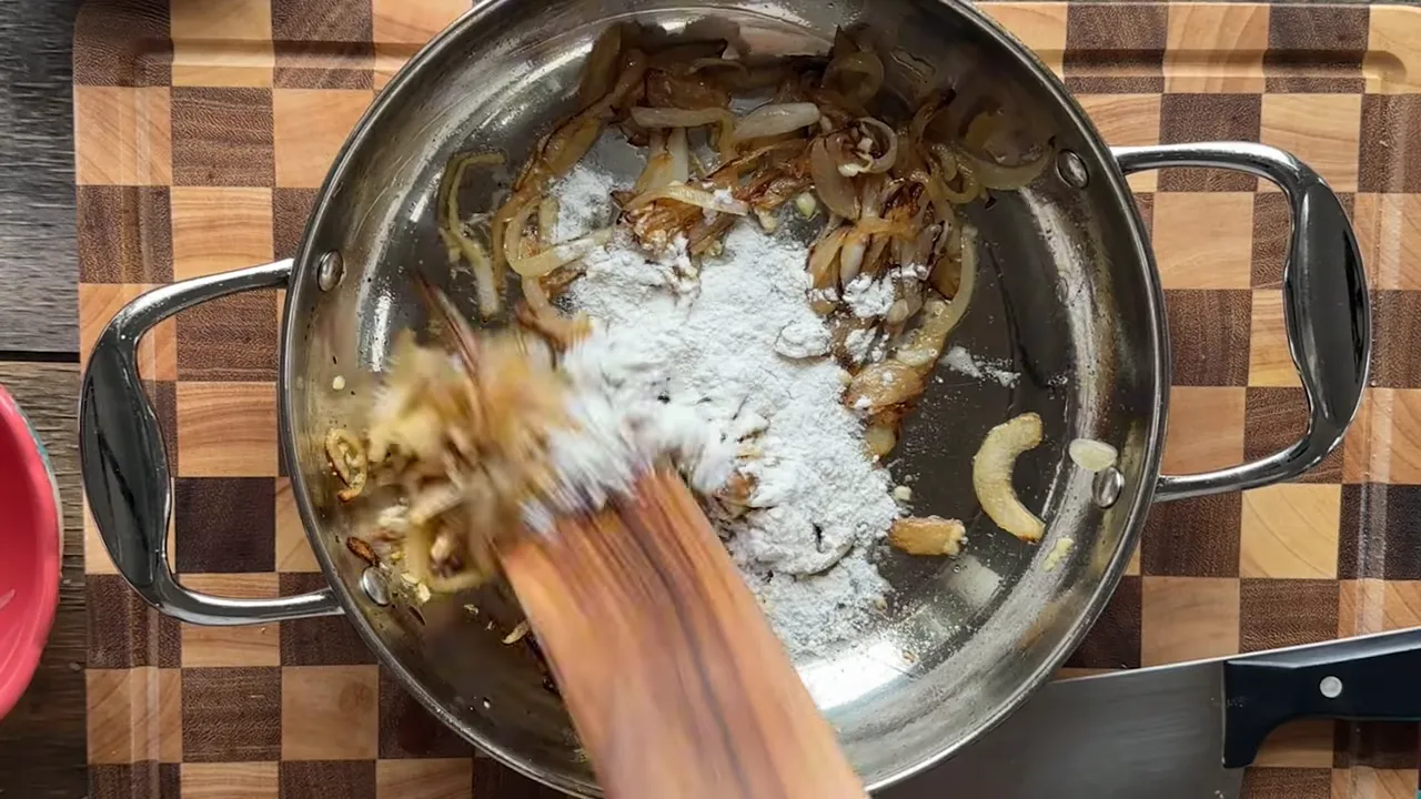 adding flour to caramelized onions in a pan to make a roux