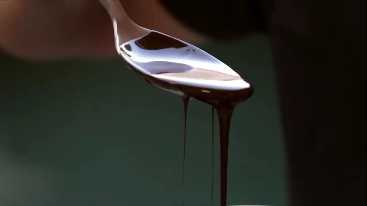 Close-up of dark melted chocolate dripping from a spoon