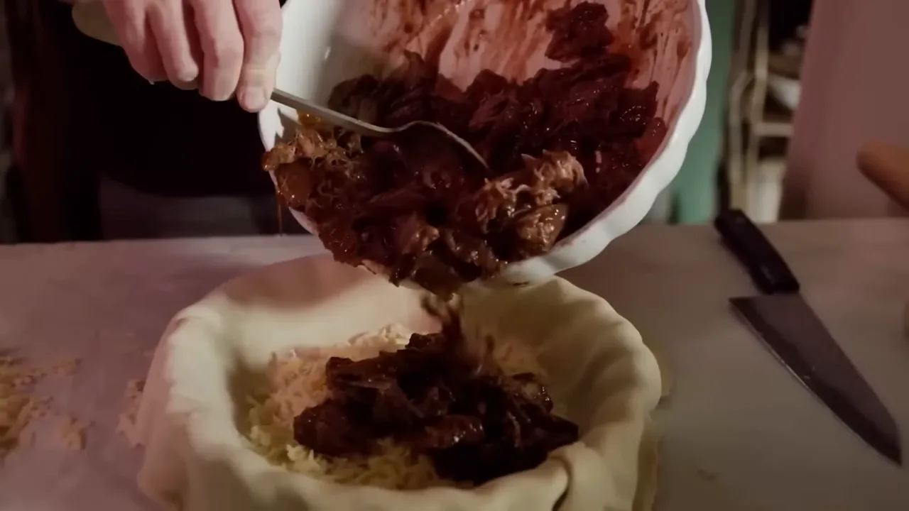 spooning short-rib and mushroom filling into a pastry-lined pie dish