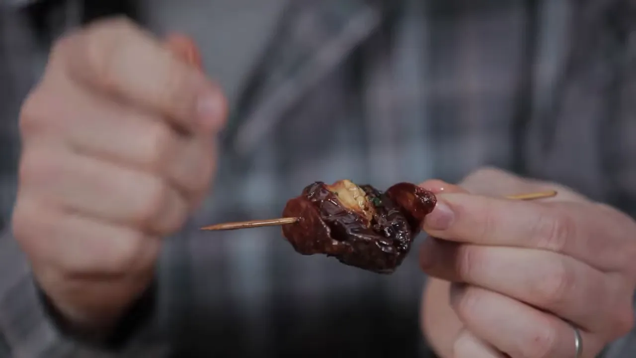 close-up of a stuffed date on a wooden skewer with visible cheese filling