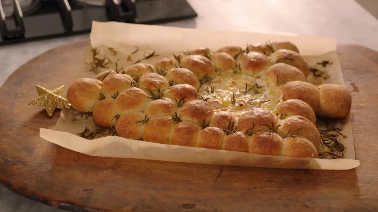 camembert-filled tear-and-share bread wreath on parchment on a wooden board, with a golden star decoration