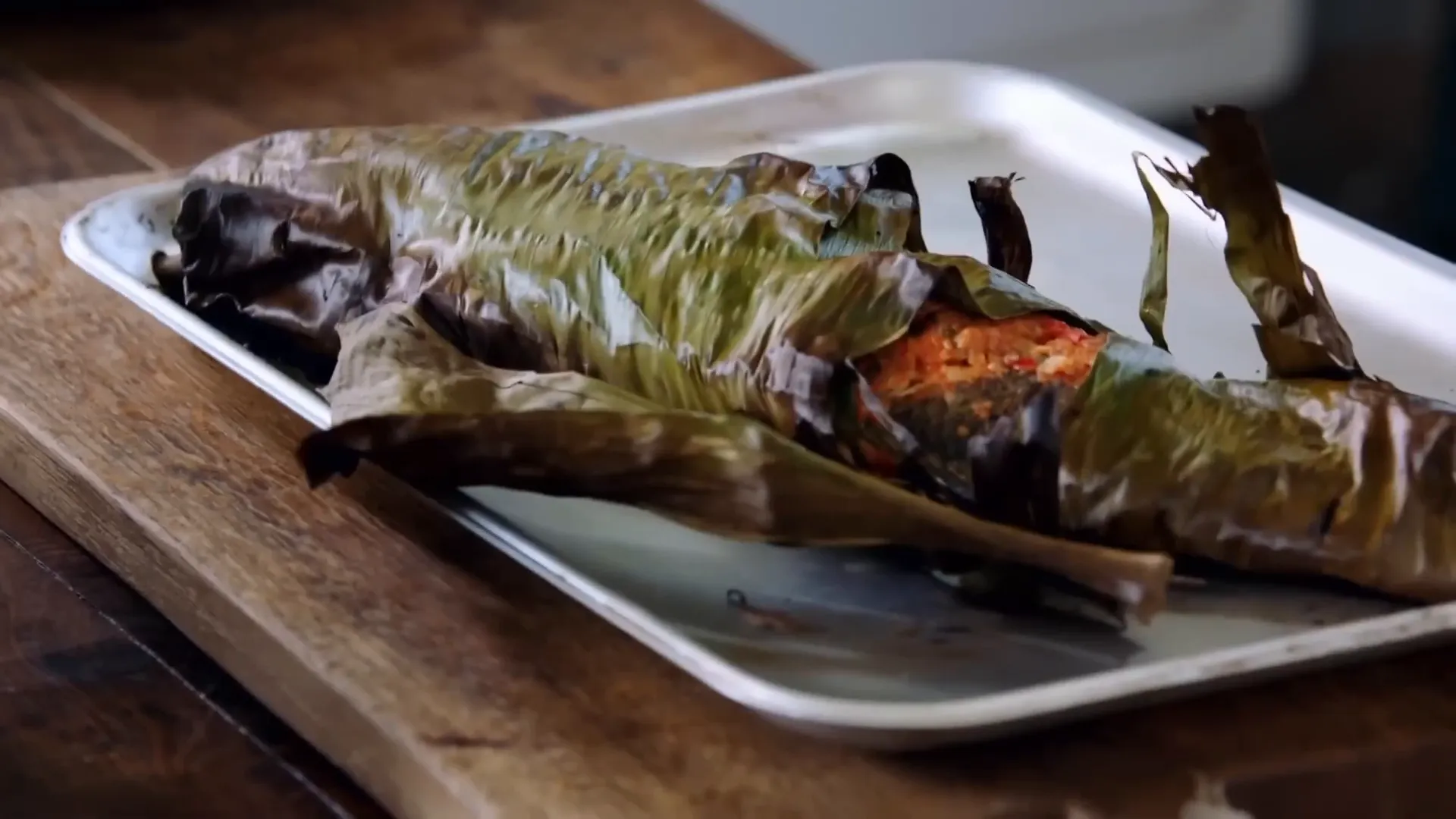 Whole sea bass wrapped in banana leaf before roasting