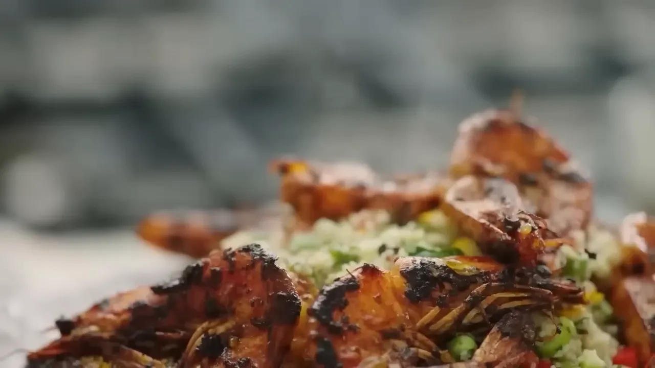 warmly spiced grilled prawns on whole wheat couscous with peas, diced peppers and herbs