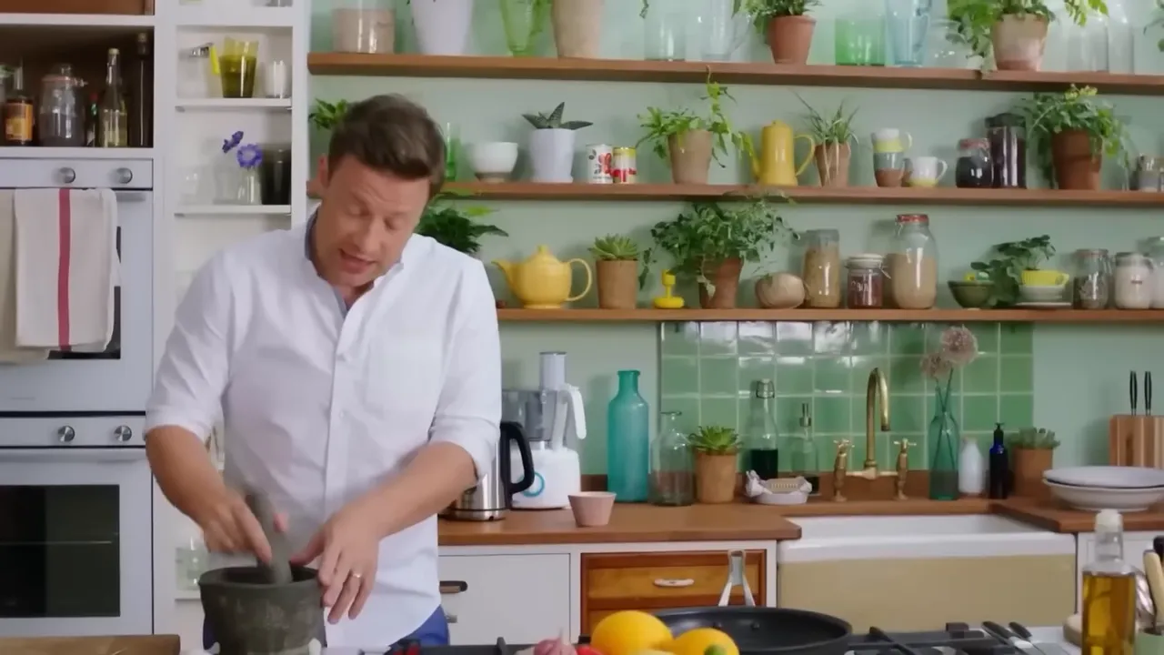 Wide shot of a home kitchen with a cook using a mortar and pestle