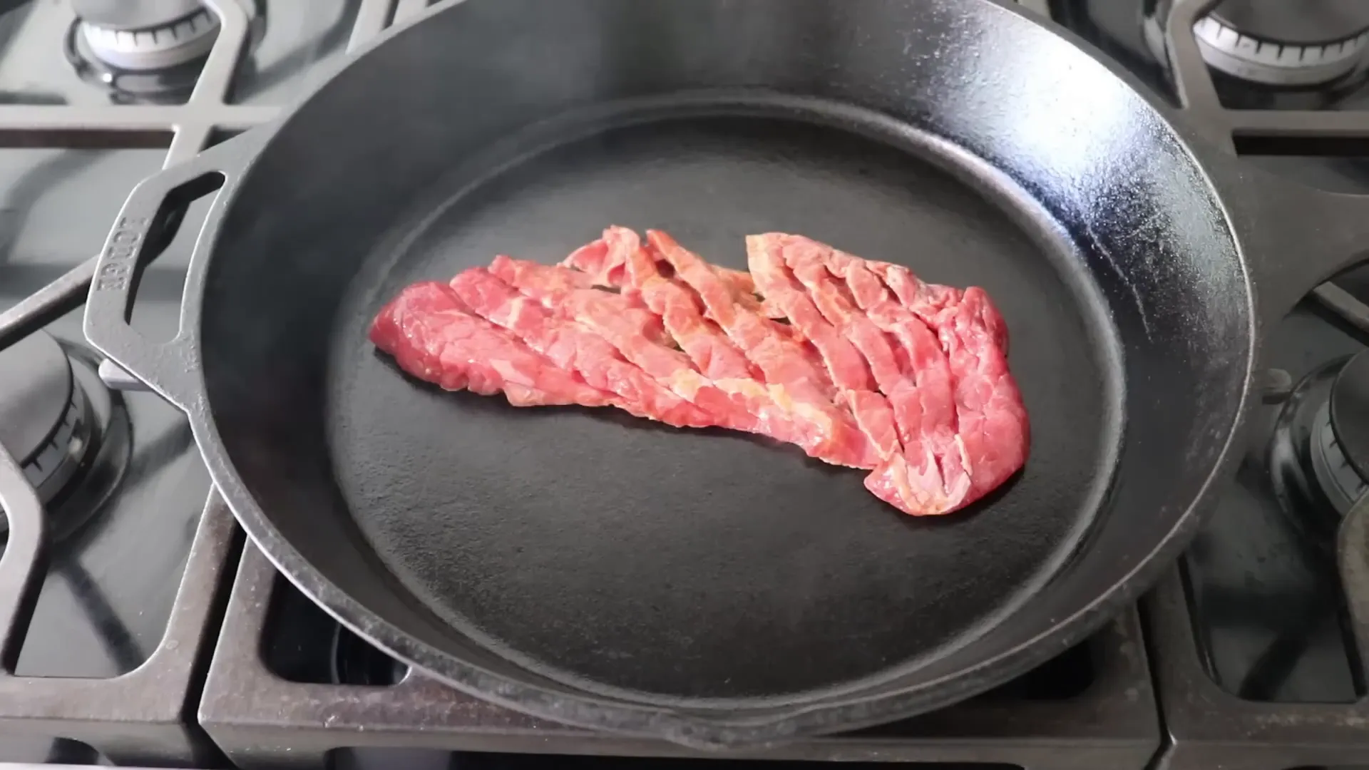 Diamond cut steak sizzling in hot cast iron pan
