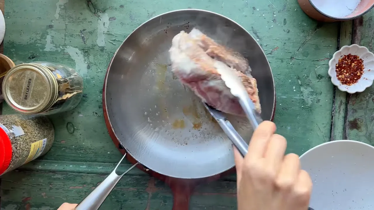Searing the pork shoulder in a hot skillet