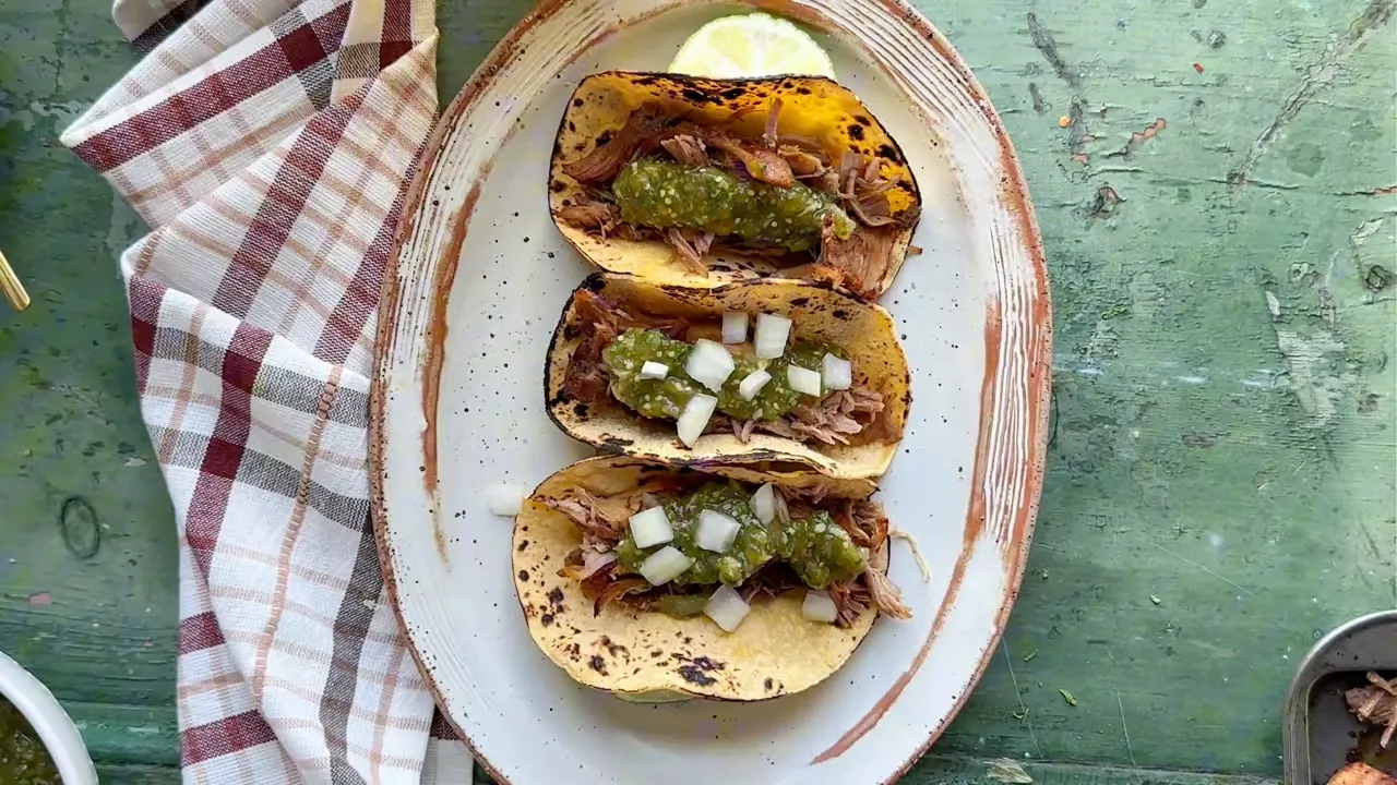 Plated carnitas tacos with salsa verde and cilantro