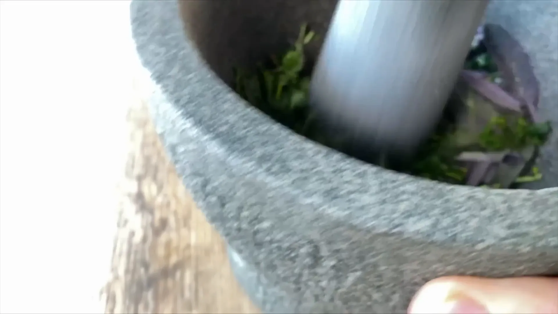 Fresh herbs being crushed with salt to release oils