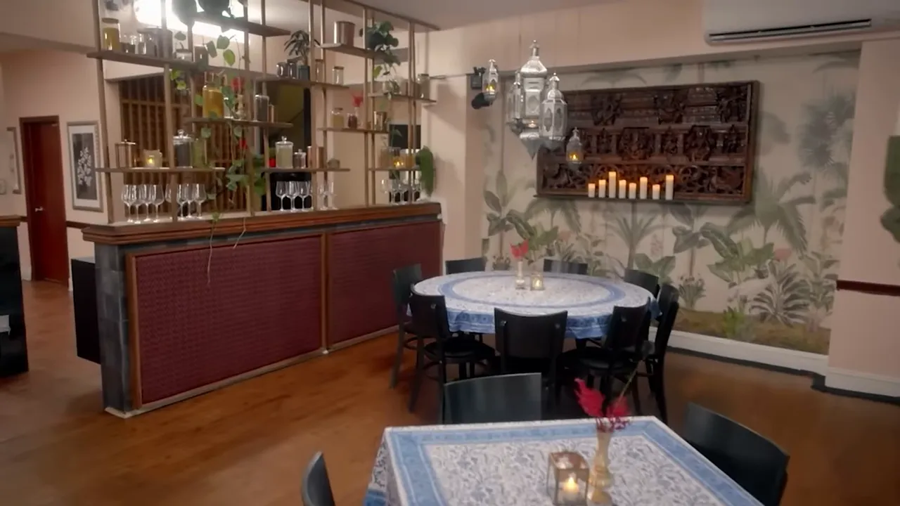 Restaurant interior with patterned tablecloths, round tables, candles and decorative shelving creating a warm atmosphere