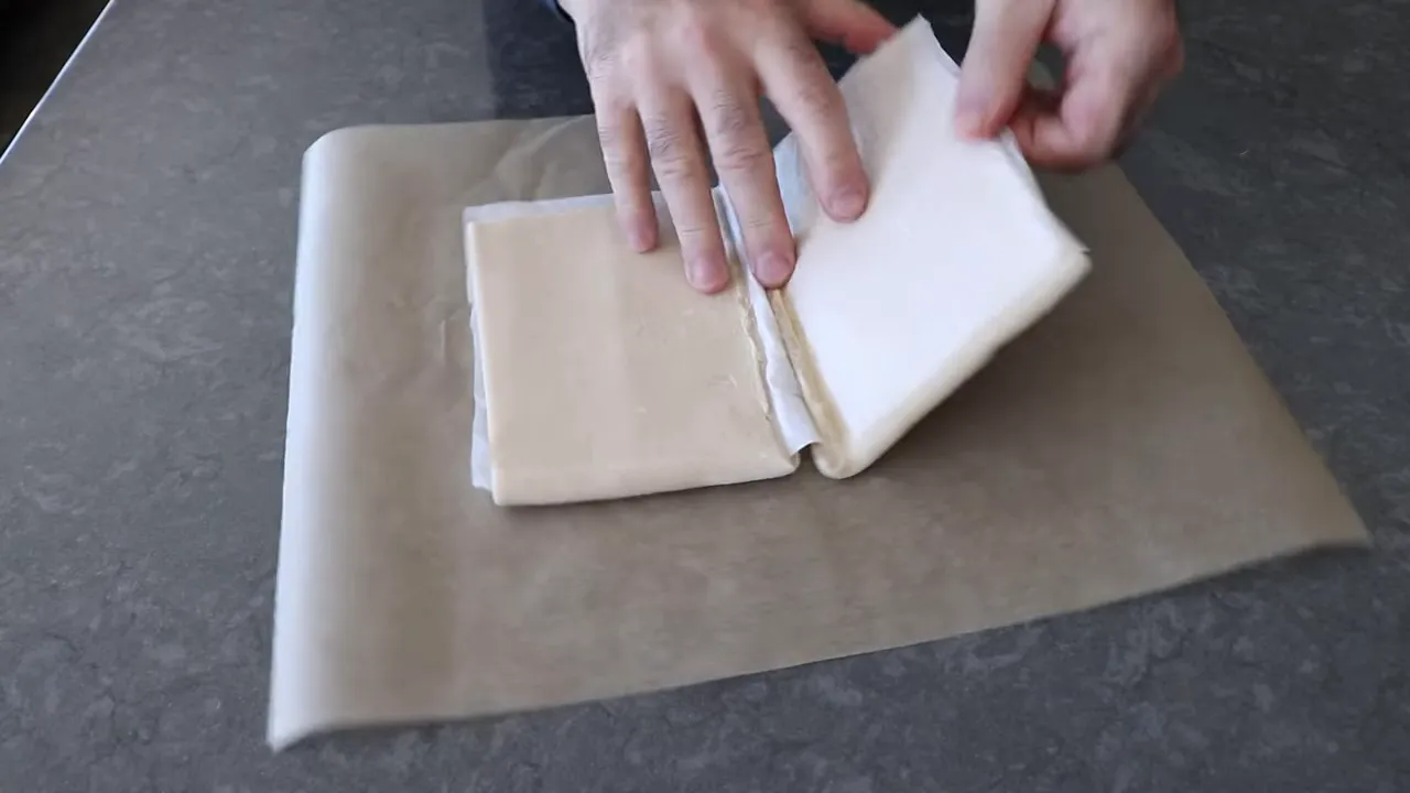 Unfolding frozen puff pastry on parchment paper