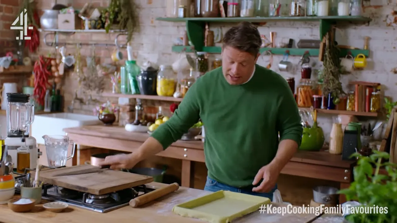Green avocado pastry dough rolled and shaped on a wooden counter with a chef preparing a quiche