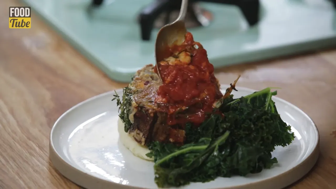 salsa being spooned over nut roast with mashed potatoes and greens