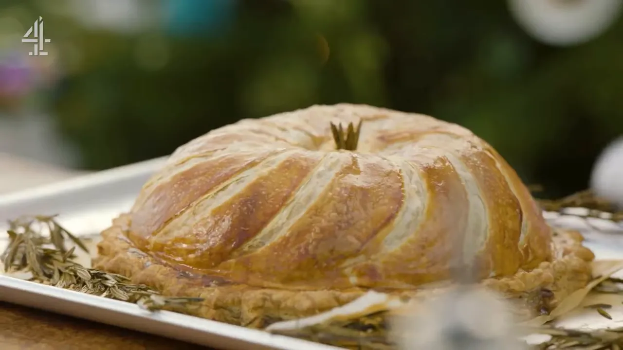Whole golden pithivier with decorative scoring on a tray