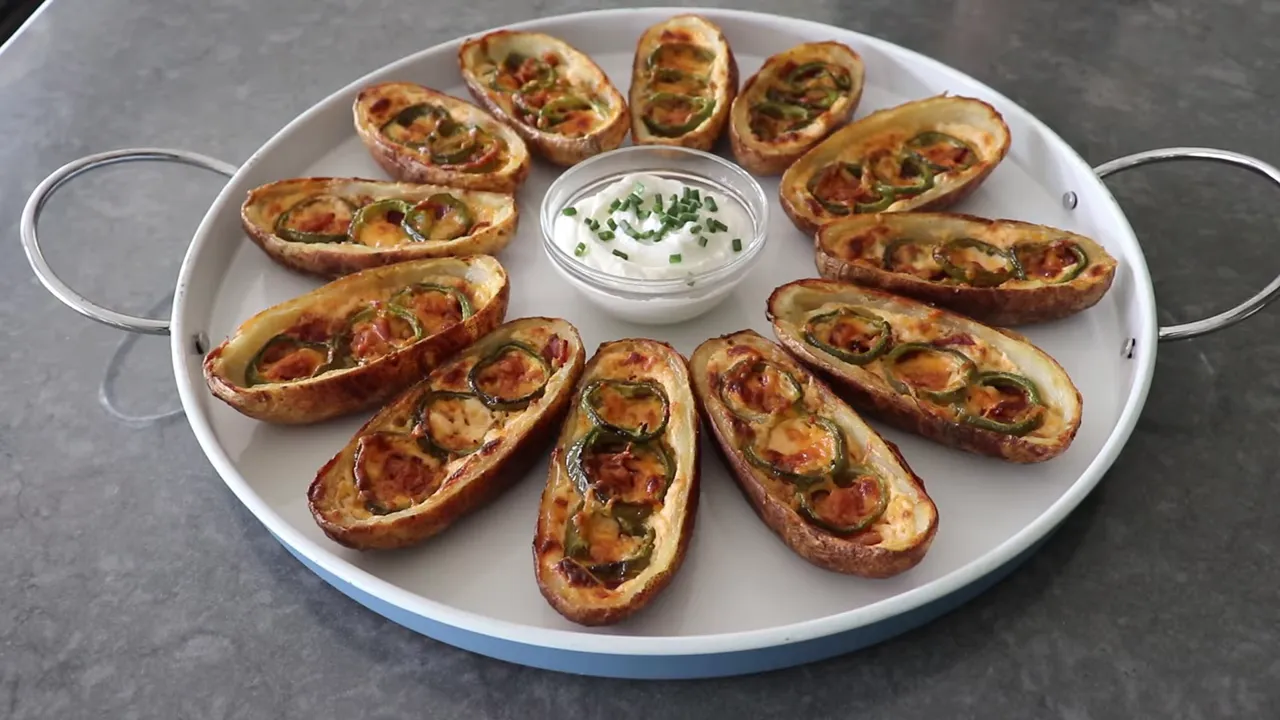 Finished jalapeno popper potato skins, golden and bubbling, served with sour cream and chives