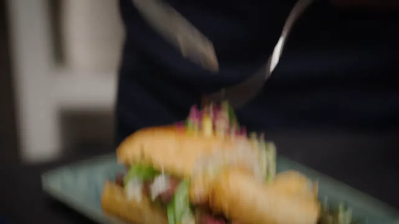 plated patty melt sandwich with greens being finished on a plate
