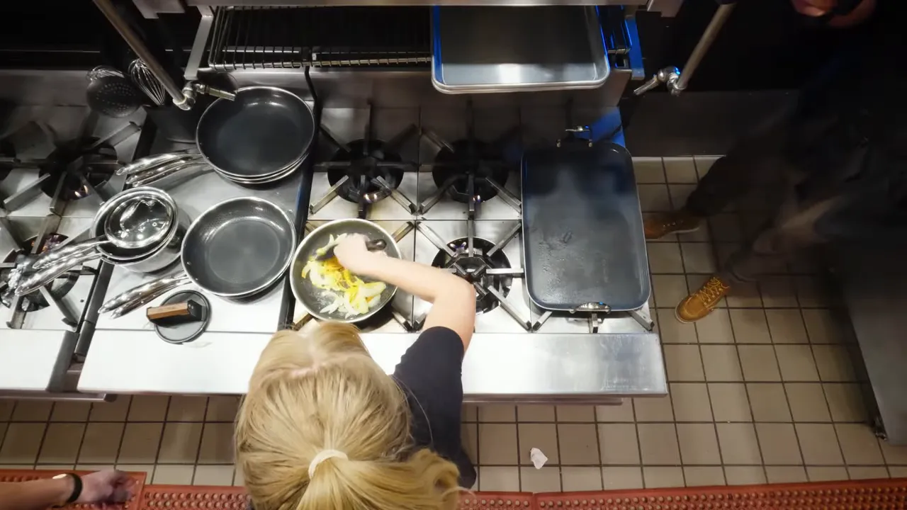 top-down view of onions cooking in a frying pan over a gas stove